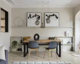 Comedor moderno con paredes color beige arena, mesa de madera, sillas grises y arte abstracto.