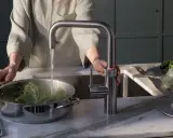 Person kocht Brokkoli mit heißem Wasser aus einem Quooker. Manche fragen sich, ob ein Quooker ungesund ist, aber hier wird er für gesunde Ernährung genutzt.