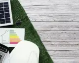 Planujesz audyt energetyczny? Sprawdź, ile kosztuje i jak poprawić efektywność energetyczną domu. Na zdjęciu panele słoneczne, kalkulator i certyfikat.