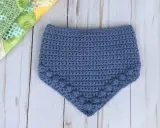 Babero azul tejido a crochet con detalle de pompones. Patrones baberos crochet instrucciones para crear esta linda prenda.