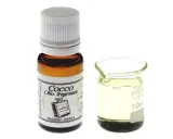 Flacone di olio di cocco fragranza, ideale per balsamo labbra, accanto a un bicchierino graduato con il liquido.