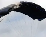 Ein großer, mehrfarbiger Fallschirm öffnet sich im Himmel, bereit für den Sprung aus dem Flugzeug.