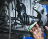 Mechanik sprawdza przegub wewnętrzny, którego uszkodzenie objawia się stukaniem podczas jazdy.