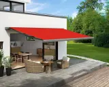 Toldo rojo extendido sobre un patio con muebles de mimbre, ofreciendo ideas para dar sombra en un patio.