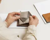 Hands examine fabric swatches, selecting the perfect butterfly lining for a project.
