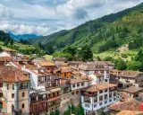 Potes, un pintoresco pueblo en los Picos de Europa, con casas de tejados rojos y montañas verdes de fondo.