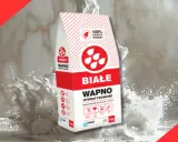 Białe wapno hydratyzowane w worku, rozsypujące się w chmurze pyłu. Idealne do prac budowlanych.