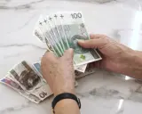 Dłonie liczą banknoty 100 zł. Zastanawiasz się, jaka emerytura z KRUS po 10 latach?