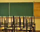 Puste krzesła odwrócone na ławkach w klasie, czekające na uczniów, kiedy idziemy do szkoły.