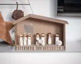 Eine einfache Krippe basteln Kinder mit Holzfiguren und Karton. Maria, Josef und das Jesuskind sind in der Mitte, umgeben von Hirten und einem Schaf.