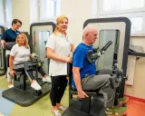 Rehabilitacja w Busko Zdrój: pan ćwiczy na siłowni pod okiem fizjoterapeutki, a pani z pomocą drugiej terapeutki. Sprawdź nasze sanatoria Busko Zdrój promocje!