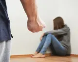 Zaciśnięta pięść mężczyzny grozi skulonej kobiecie. Scena symbolizuje agresję żony wobec męża, przemoc domową.
