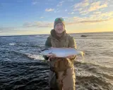 Glad fiskare med en fin öring vid havet, en lyckad dag med **trout fishing** i Sverige.