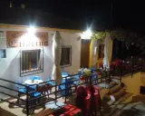 Bar Endrino, un lugar acogedor donde comer en Segura de la Sierra. Mesas y sillas azules y rojas esperan bajo luces cálidas.