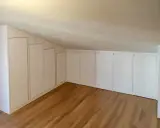 Armadi su misura sfruttano ogni centimetro, perfette idee sottotetto molto basso. Pavimento in legno chiaro.