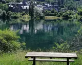 Un banco de madera invita a contemplar el embalse de Lanuza, con un pueblo de tejados grises reflejado en sus tranquilas aguas verdes.
