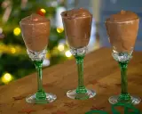 Tre glas med krämig chokladmousse, perfekta för ett enkelt chokladmousse recept. Julbelysning i bakgrunden skapar en festlig stämning.