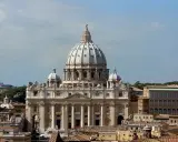 La majestueuse hauteur de la basilique Saint-Pierre domine le ciel romain, ses dômes imposants se détachant sur un ciel bleu clair.