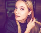 Junge Frau mit blonden Haaren, die sich die Haare für die Olaplex No. 0 Anwendung zurechtmacht.