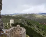 Un piccolo santuario domina il paesaggio del **cammino del Gran Sasso**, tra colline verdi e montagne nebbiose.