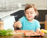 Mała dziewczynka przygotowuje łososia, bogate źródło witaminy A, do posiłku.