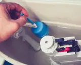 Main tenant répare chasse d'eau bouton poussoir. Il ajuste le flotteur bleu pour un bon fonctionnement.