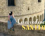 Donna seduta su un muretto di pietra, con vista panoramica. Un'ottima pausa durante il trekking a San Leo.