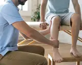 Un podologue examine la jambe d'un patient, un examen essentiel pour la podologie.