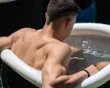 Mann sitzt im Eisbad, bereit für das warme Duschen danach.
