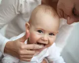 Mama pomaga dziecku z kolejnością wychodzenia zębów, delikatnie masując dziąsła palcem w nakładce.