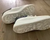 Białe sneakersy Alexander McQueen z granatowymi brokatowymi wstawkami. Zwróć uwagę na charakterystyczną podeszwę, by jak rozpoznać oryginalne buty Alexander McQueen.