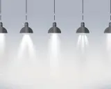 Pięć wiszących lamp tworzy oświetlenie miejscowe, rzucając snopy światła na pustą przestrzeń.