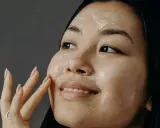 Donna applica una crema sul viso, un gesto quotidiano per come curare la pelle del viso.