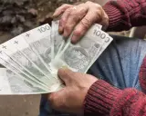 Dłoń trzyma wachlarz banknotów 100 zł. Czy to uczciwy zarobek, czy szalbierstwo?