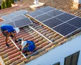 Dos técnicos instalan placas solares en un tejado. Aprendiendo como instalar placas solares para un futuro energético.