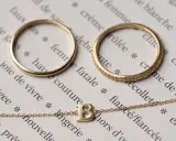 Anelli e collana in oro 14 carati, che significa un gioiello di qualità, su pagine di un libro con parole francesi.