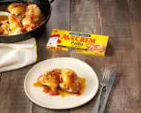 Sabroso pollo con sopa de cebolla y cerveza, servido en sartén y plato. Caja de Avecrem Pollo al lado.