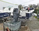 Un homme effectue le rinçage moteur hors bord vinaigre blanc d'un bateau. L'hélice est immergée dans une cuve remplie de liquide.