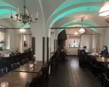 Mysig interiör på Cafe Kronhuset med välvda tak och varma ljus. Två personer sitter vid ett bord och samtalar.