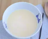 En skål med krämig vaniljsås, perfekt för ditt vaniljsås recept. En vaniljstång ligger bredvid.