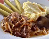 Karkówka pieczona w plastrach z cebulą, podana z puree ziemniaczanym, ogórkami kiszonymi i grzybami.