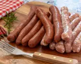 Merguez et saucisses crues sur planche en bois, prêts pour le barbecue. Le temps de cuisson parfait est essentiel pour un délice savoureux.