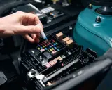 Mano insertando un fusible en la caja de fusibles del coche.
