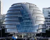 Edificio iconico di Norman Foster, con facciata a diamante in vetro, riflette il cielo e gli edifici circostanti.