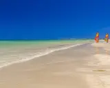 Piękna pogoda w Tunezji w marcu. Trzy kolorowe deski windsurfingowe na piaszczystej plaży, turkusowa woda i błękitne niebo.