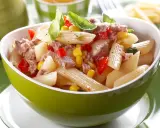 Ein leckerer nudelsalat mit thunfisch, Mais und Paprika, garniert mit Basilikum.