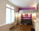 Aménagement petit studio optimisé avec lit mezzanine, canapé confortable et rangements intégrés. Un espace de vie fonctionnel et stylé.