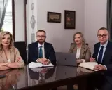 Cztery osoby w strojach biznesowych siedzą przy stole w sali konferencyjnej.