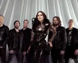 Within Temptation Sverige: Sharon den Adel i sin glittrande klänning, omgiven av bandmedlemmar i mörka kläder, framför en vit draperad bakgrund.