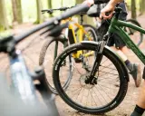 Przygotowania do amatorskich rajdów rowerowych w lesie. Dwa rowery górskie, jeden zielony, drugi żółty, stoją na leśnej ścieżce.